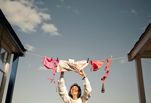 Woman removing dried clothes during sunny day