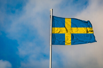 A Flag of Sweden flying on a Flagpole against the Sky