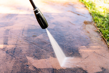 Cleaning dirty backyard paving tiles with pressure washer cleaner.