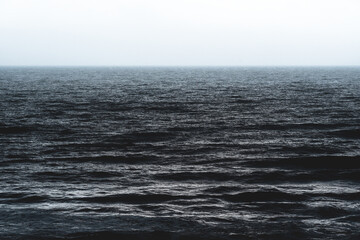 Texture of the cark blue silver shining ocean during storm in Spain