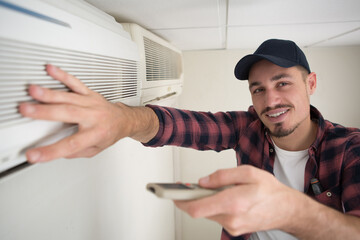 technician testing air conditioning unit with remote control