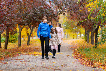Fototapeta premium children run along the path in the autumn park . they play and laugh, they have a lot of fun. they are surrounded by beautiful nature and trees with yellow and red leaves