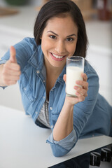Fototapeta premium woman holding a glass of milk with thumbs up