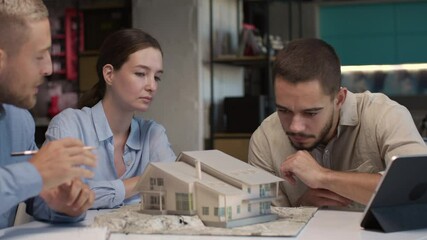Architects and designer work on house layout in office studio. Group of creative people at table talking on manufacture and discussing home design. Specialist looking at detailed projection of model