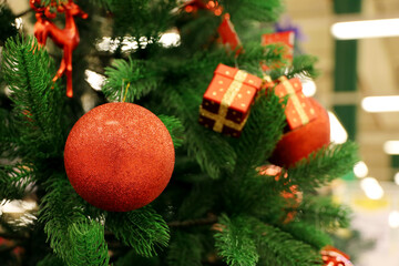 Fototapeta na wymiar Christmas tree with decorations on blurred lights background. Red toy balls and gift boxes on a branches, New Year celebration