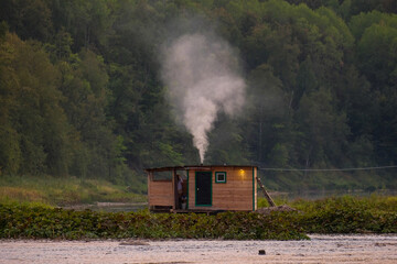 Wooden bathhouse on the river. A small house in the center of the frame