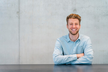 Smiling young businessman with arms crossed at table