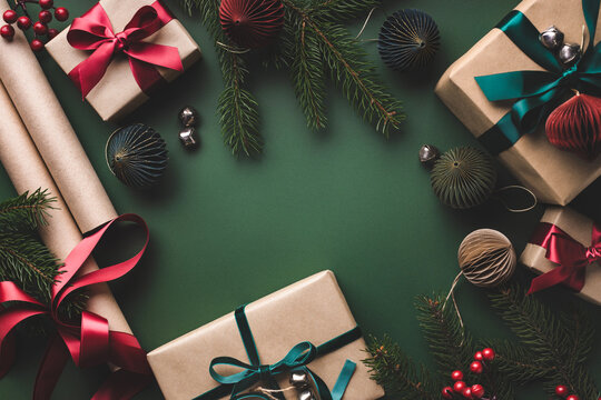 Christmas background with gift boxes, paper's rools and decorations on green.