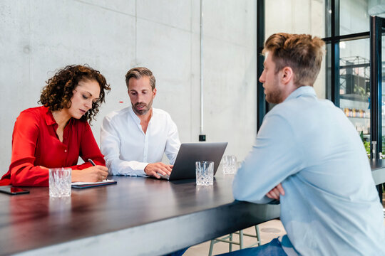 Recruiter writing in paper while taking job interview of candidate at office