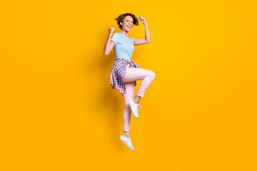 Fototapeta na wymiar Full length body size view of attractive cheerful overjoyed girl jumping having fun isolated over bright yellow color background