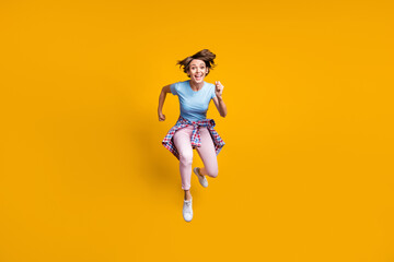 Fototapeta na wymiar Photo portrait full body view of woman running to camera with tight waist shirt jumping up isolated on vivid yellow colored background