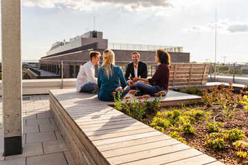 Coworkers with cross-legged sitting on rooftop