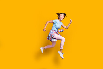 Fototapeta na wymiar Photo portrait full side body view of crazy girl running with tight waist shirt jumping up isolated on vivid yellow colored background