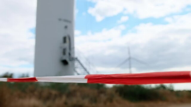 Signal tape marking the boundaries of the restricted area in case of emergencies or repair work on the background of the wind turbine.