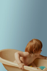 Long haired white caucasian ginger toddler plays in the bathroom copy space negative space background