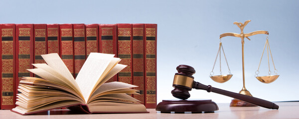 Legal Law and Justice concept - Open law book with a wooden judges gavel on table in a courtroom or law enforcement office. Copy space for text. - 469261107