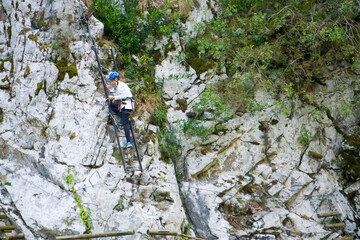 Athlete man in protective helmet climbing a rocky mountain.