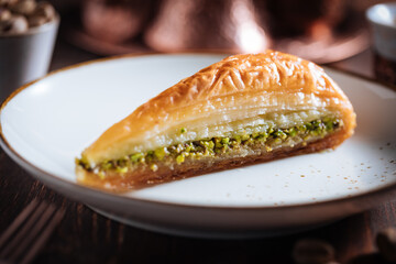 Turkish or Bosnian dessert called Baklava with pistachio served with traditional Turkish or Bosnian coffee set on a wooden board in moody atmosphere