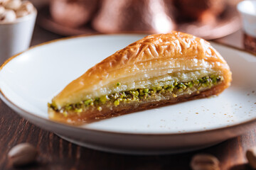 Turkish or Bosnian dessert called Baklava with pistachio served with traditional Turkish or Bosnian coffee set on a wooden board in moody atmosphere