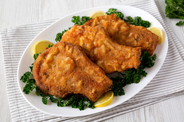 Homemade Fried Pork Chops on a White Plate, low angle view.