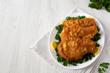 Homemade Fried Pork Chops on a White Plate, side view.