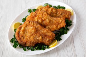 Homemade Fried Pork Chops on a White Plate, low angle view.