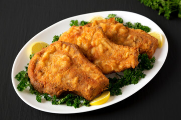 Homemade Fried Pork Chops on a White Plate, side view.