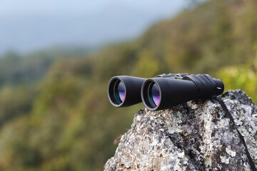 binoculars on top of rock mountain at sunset