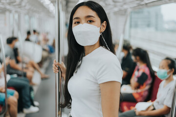 Fototapeta na wymiar Asian woman wearing protective mask in a train. woman wearing surgical protective mask in a public transportation. New normal concept.