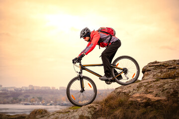 Cyclist Riding the Mountain Bike Down Rocky Hill at Autumn Evening. Extreme Sport and Enduro Cycling Concept.