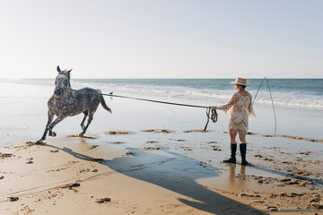 Horse running around pregnant woman with whip at beach