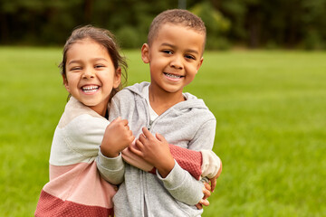 childhood, leisure and people concept - happy smiling little boy and girl hugging at park - 469265569