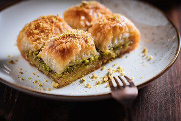 Turkish or Bosnian dessert called Baklava with pistachio served with traditional Turkish or Bosnian coffee set on a wooden board in moody atmosphere