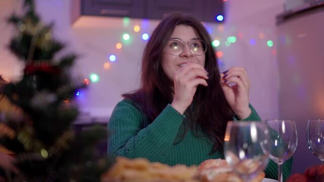 Pretty armenian woman sitting at dinner table, talking and laughing with friends on Christmas Eve 2022. Concept of Celebrating New Year with our close ones