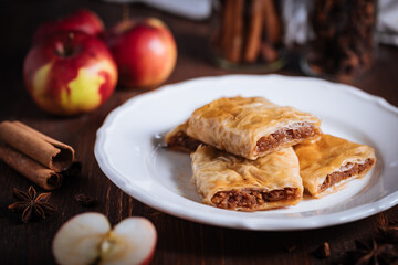 Turkish or Bosnian dessert called Baklava with pistachio served with traditional Turkish or Bosnian coffee set on a wooden board in moody atmosphere