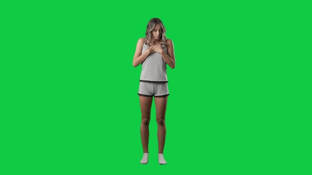 Shocked scared and disgusted young woman reaction in pajama looking at camera. Super slow motion. Full body isolated on green screen background