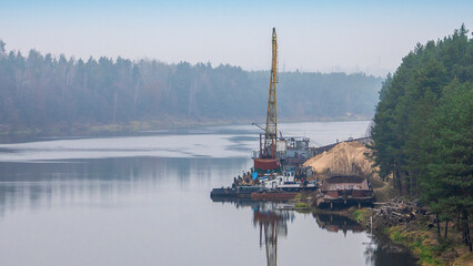 Floating crane on the river. Dredging crane working near shore. Conservation river flow. Nature, river, sky, clouds.