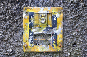 Damaged & Worn Yellow Metal Fire Hydrant Sign on Rough Textured Wall