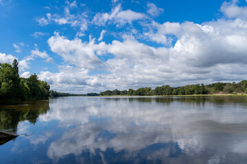 Calm waters of the Loire reflect the bright blue sky, seen from the popular Loire à Vélo cycle path.