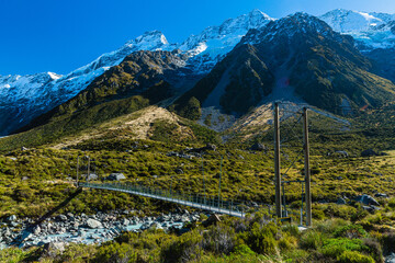 ニュージーランド　アオラキ・マウント・クック国立公園のフッカー・バレー・トラックのトレッキングコースにある第三の吊り橋と後ろにそびえる南アルプス山脈のセフトン山