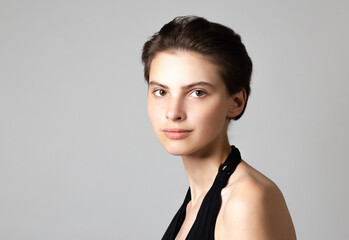 Beautiful young woman with absolutely no makeup on a neutral gray background