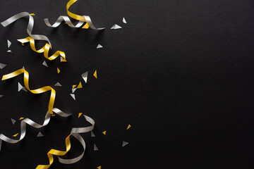 close up on group of gold and silver color of rolling ribbon and confetti on black background with copy space for merry christmas, happy new year festival and black friday sale season concept