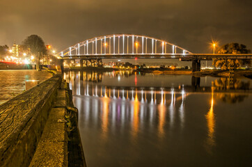 Deventer, The Netherlands, November 13, 2021: view along the quay of the river IJssel towards the illuminated Wilhelmina bridge