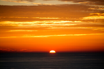 Sunset, behind the clouds over the sea