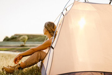 White woman sitting in tent during camping on summer day © Drobot Dean