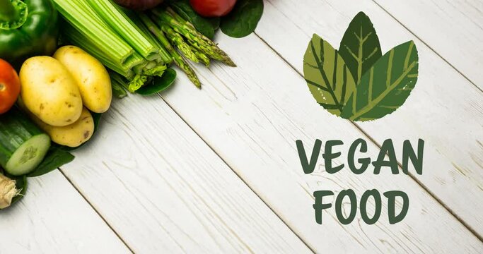 Animation of vegan food text in green, with leaves over fresh vegetables on white boards