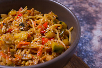Stir fry noodles with vegetables on dark bowl.