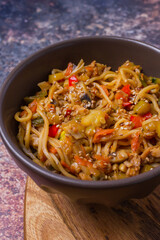Stir fry noodles with vegetables on dark bowl.