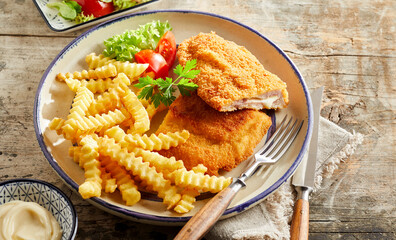 Schnitzel cordon bleu and crinkle fries on table