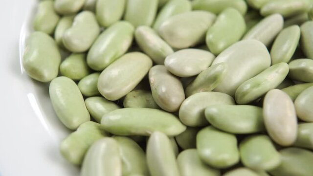 Spanish traditional verdina green beans. Full white bowl. Macro. Slow rotation. Dry raw legumes. Asturian cuisine